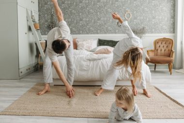 A family stretches together in a cozy bedroom, enjoying morning activities.